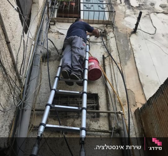 אדם על סולם מתקן צינורות חיצוניים